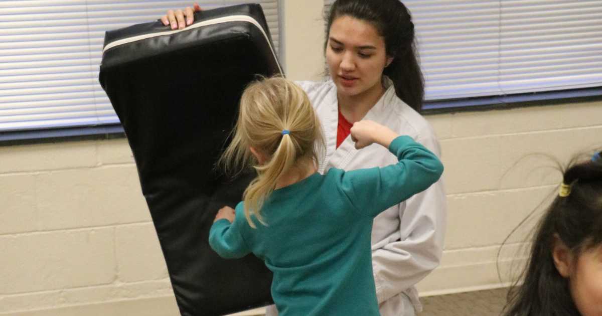Instructor helps student with taekwondo 
